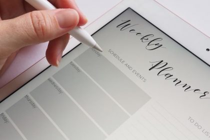 A stylus writing in a digital weekly planner on a tablet screen, ideal for organization.