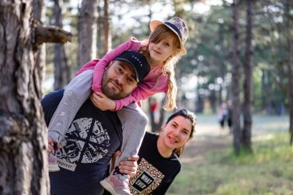 A joyful family enjoying a playful day in a sunlit forest park, capturing the essence of togetherness.